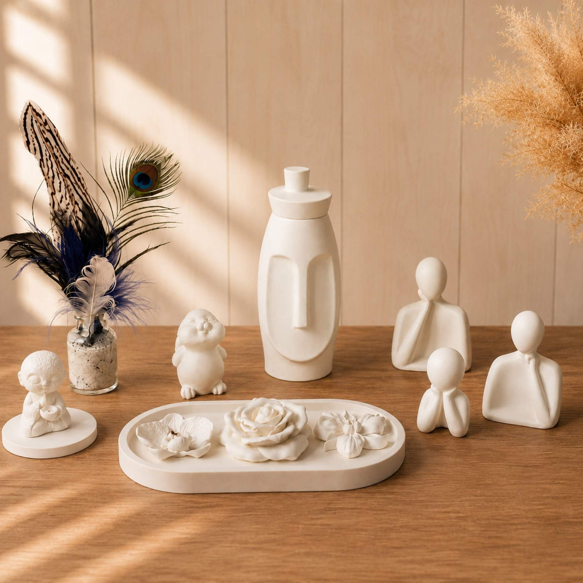Trois figurines blanches minimalistes parfumables à côté d'autres créations de Décoplumes
