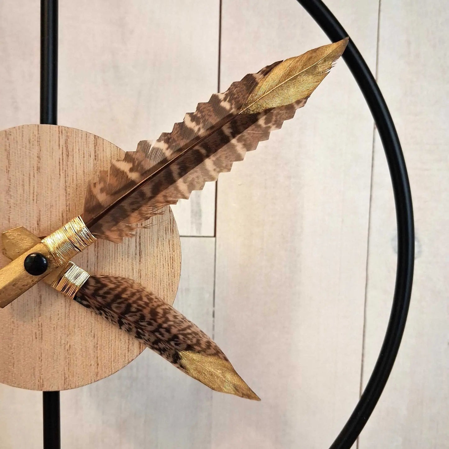zoom sur les aiguilles en plumes de l'horloge avec finition dorée sur l'extrémité des plumes