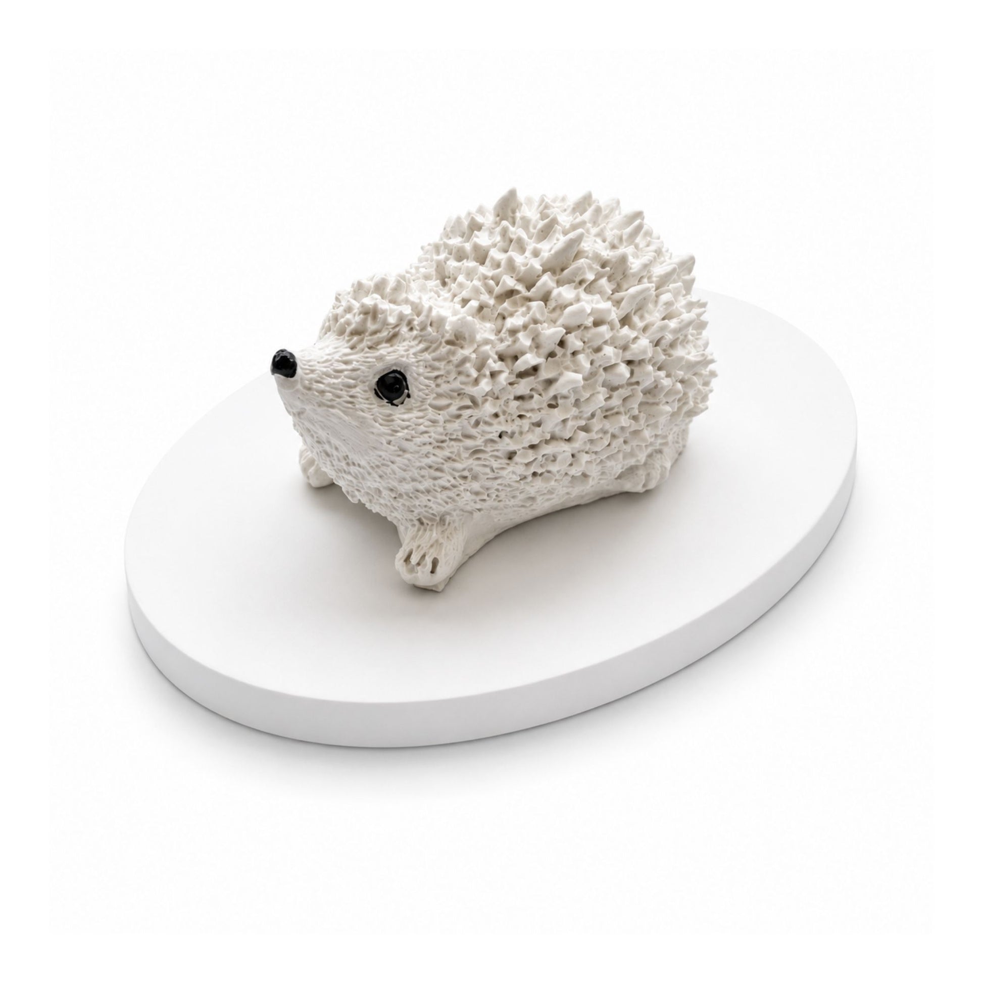 Petit hérisson décoratif blanc à parfumer en matière minérale artisanale présenté sur un plateau ovale assorti