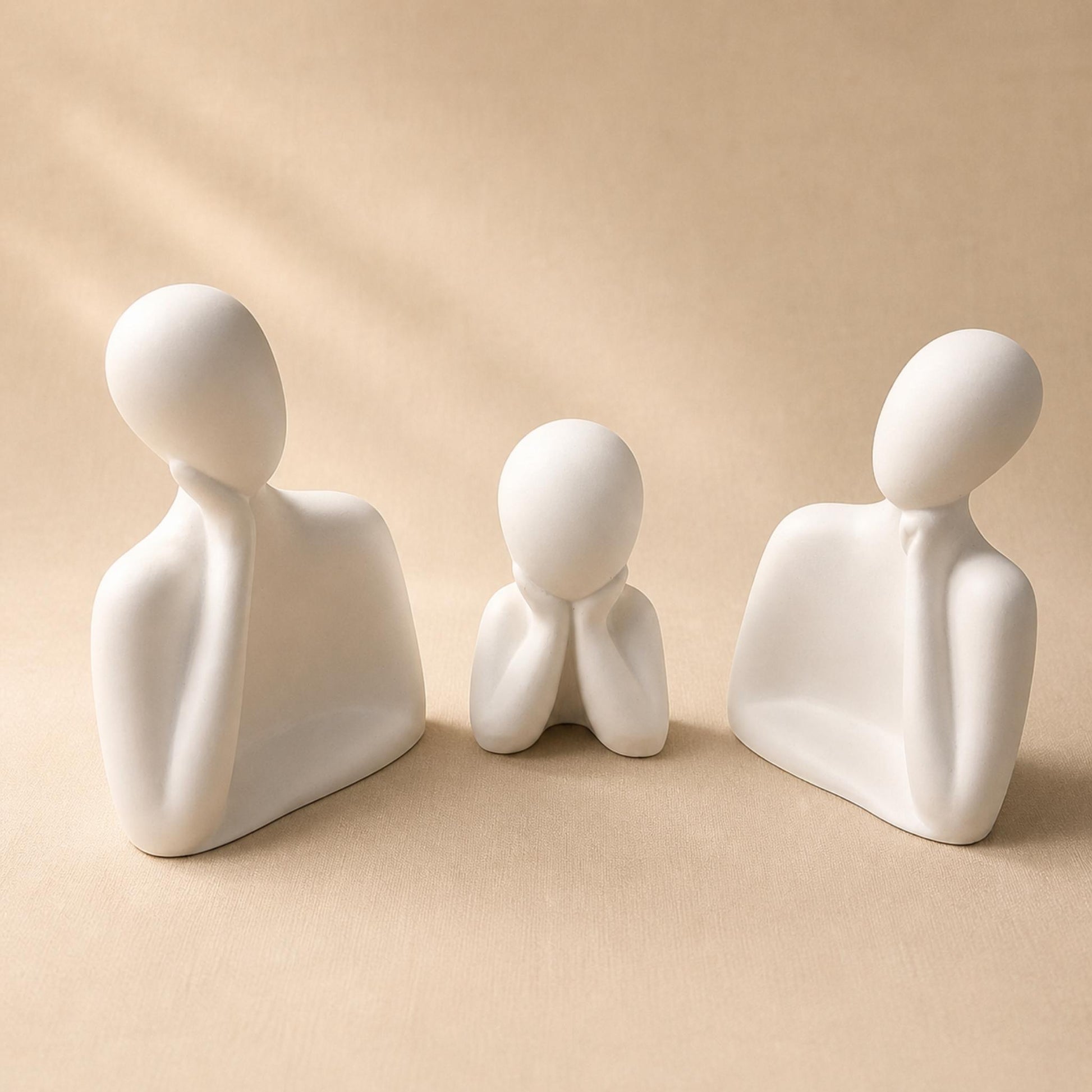 Trois figurines blanches minimalistes parfumables sur fond beige clair, création de Décoplumes