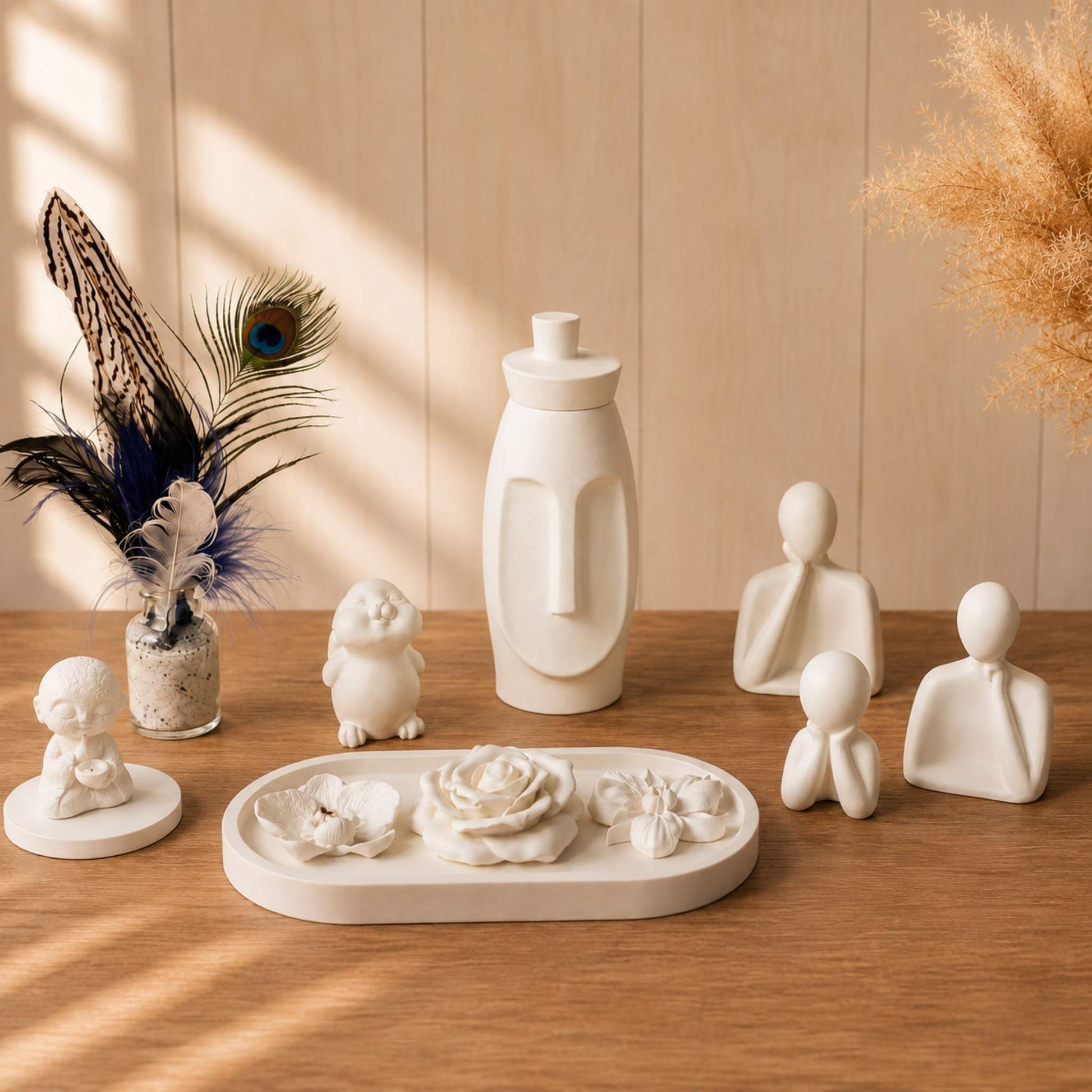 Trois figurines blanches minimalistes parfumables à côté d'autres créations de Décoplumes